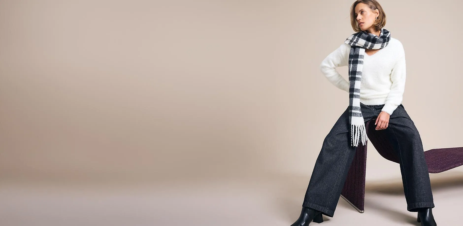 Flauschiger wei&szlig;er Pullover, karierter Schal, weite dunkle Hose und stylische Stiefeletten.