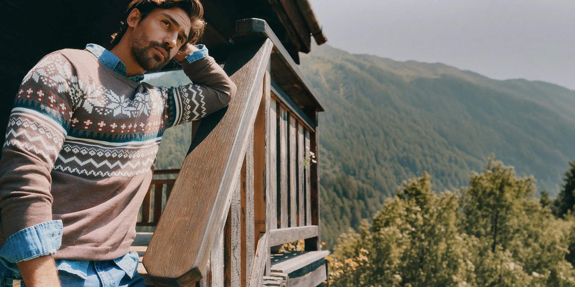 Maglione lavorato a maglia marrone con motivo ricco di dettagli, abbinato a una camicia di jeans blu.