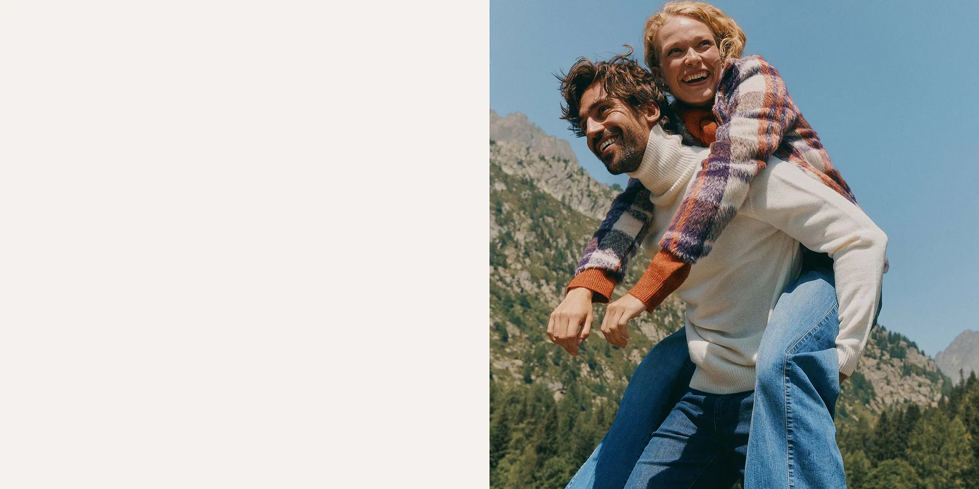 Uomo con jeans azzurri e dolcevita bianco che porta in spalla donna con jeans a zampa azzurri e giacca a quadri bianca, viola e arancione.