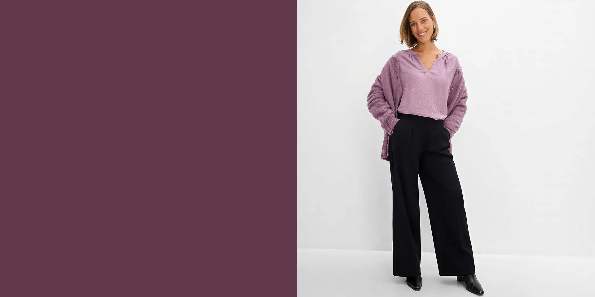 Indossa una camicetta viola, abbinata a un cardigan di maglia e a un paio di pantaloni larghi neri.