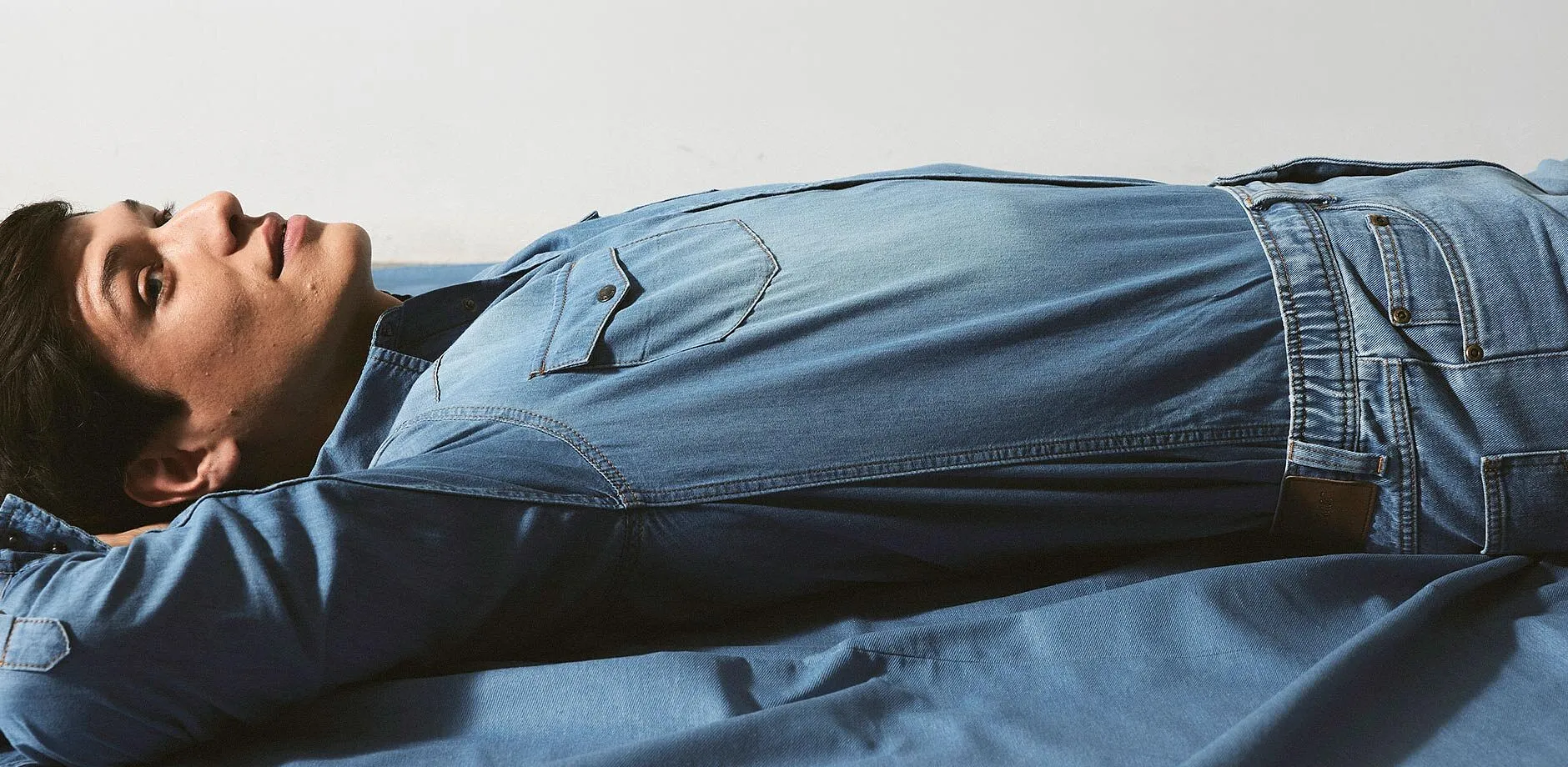 Jeans blu attillati con cuciture in evidenza e una toppa in pelle marrone.