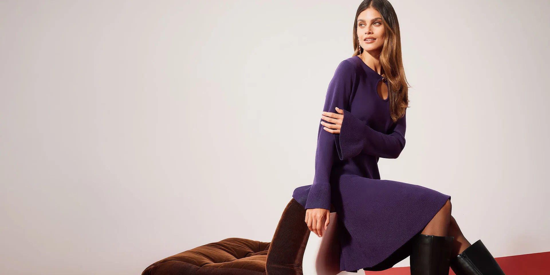 Elegante abito viola in maglia con maniche ampie, abbinato a stivali neri alti.