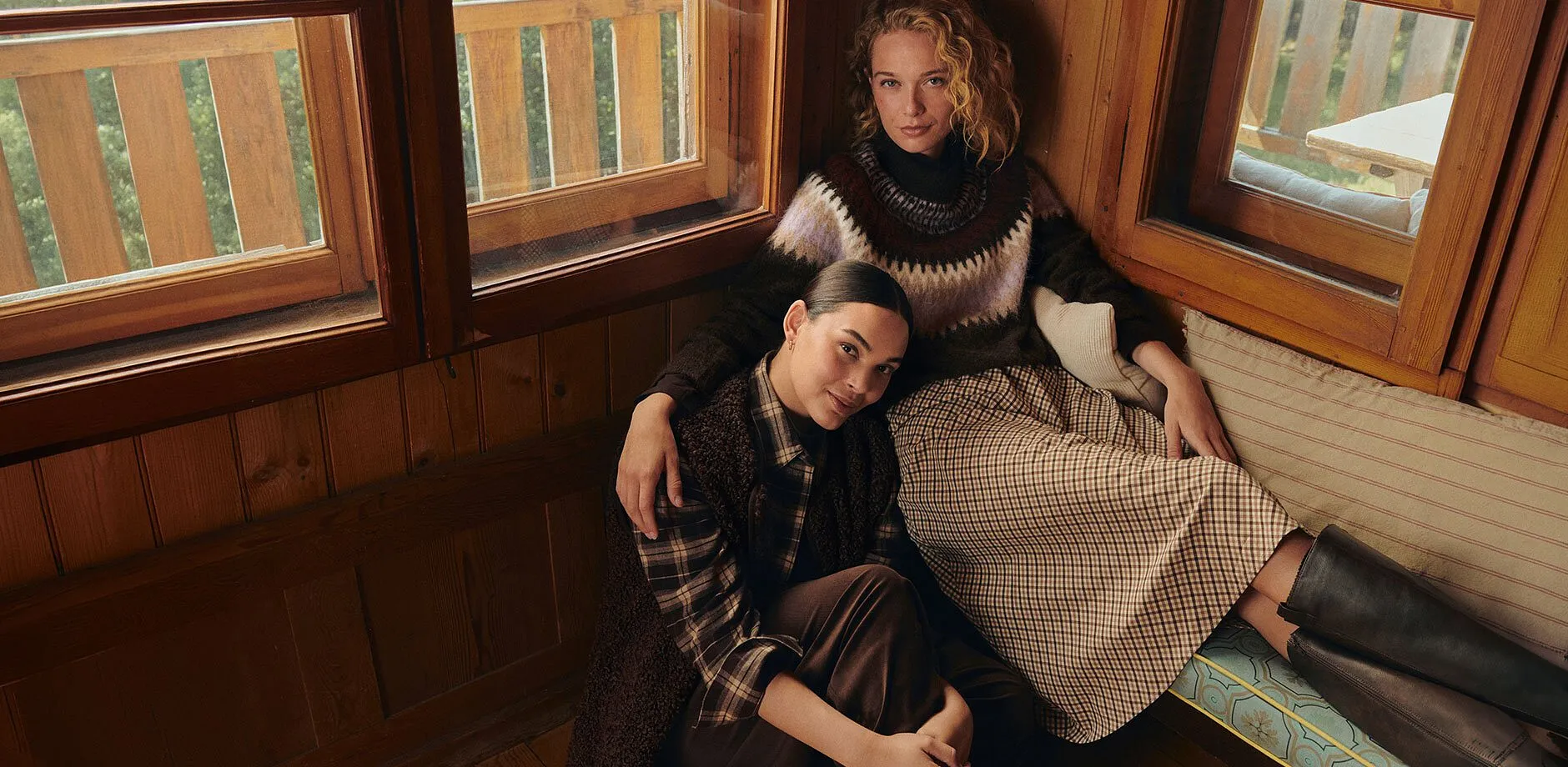 Abbigliamento comodo e avvolgente con maglione lavorato a maglia, gonna a quadri, camicia a quadri, gilet e pantaloni marroni.