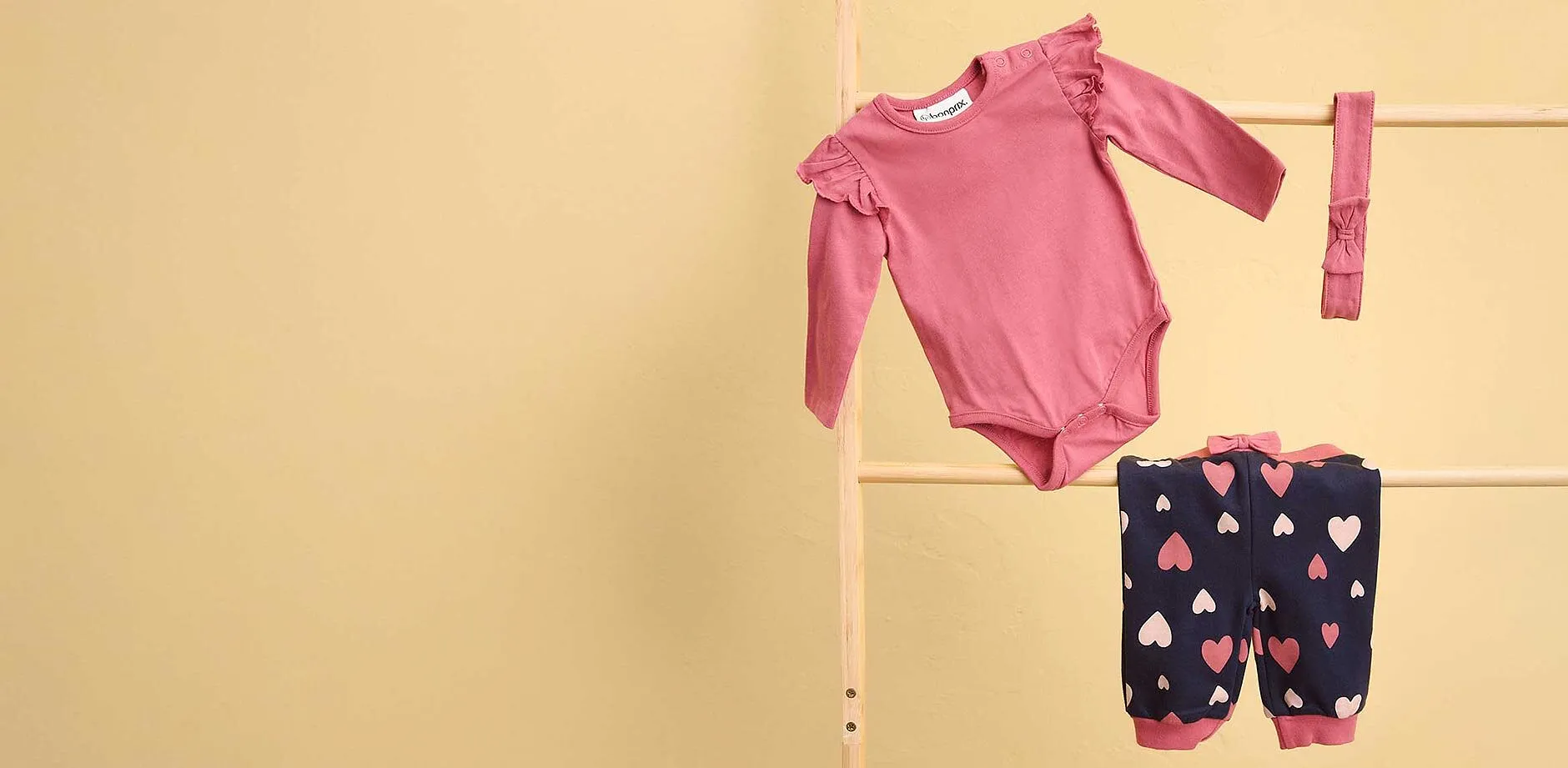 Dolce set per neonati: body rosa e pantaloni blu scuro con motivo a cuori.