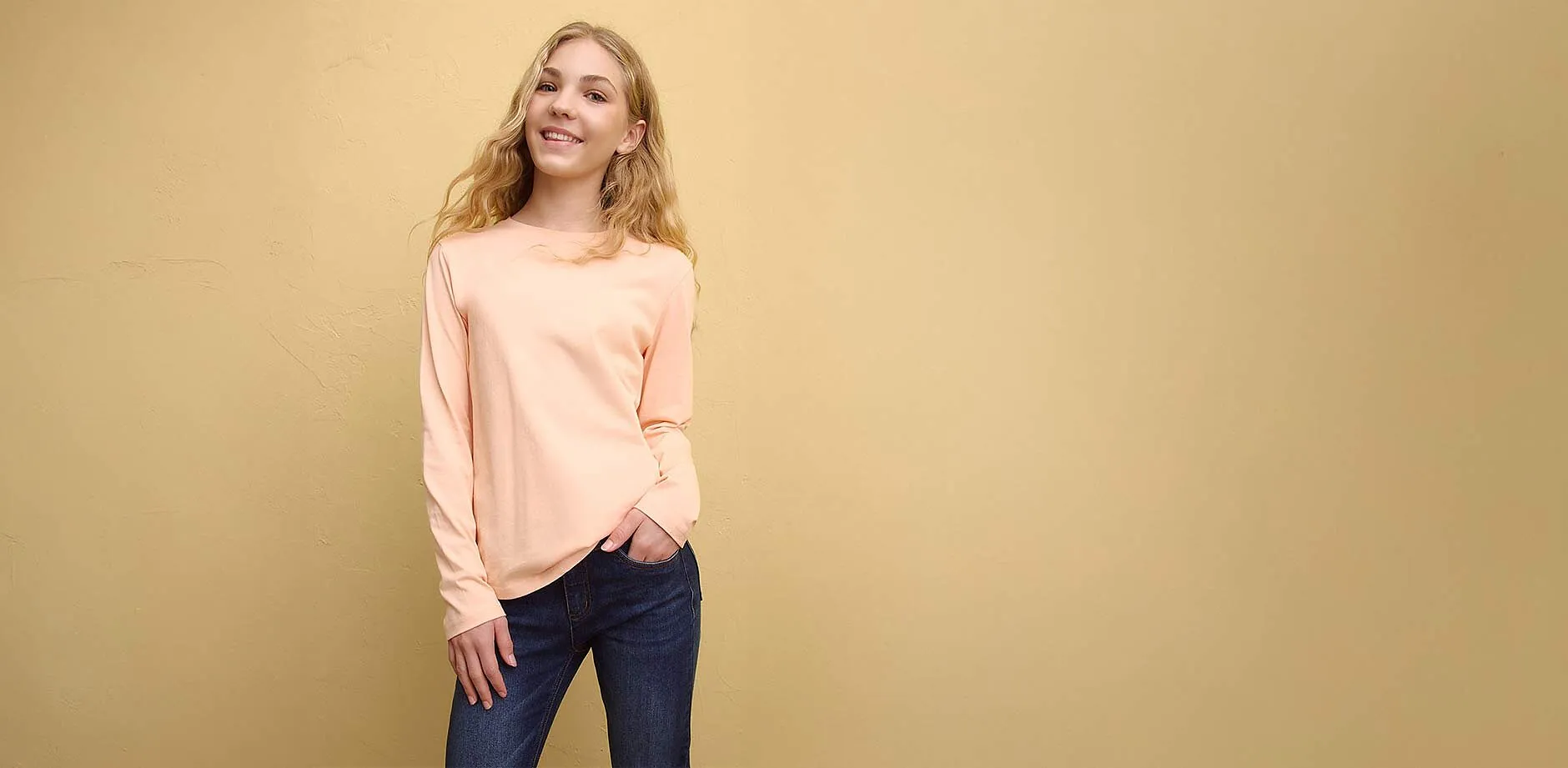 Maglietta blu a maniche lunghe con stampa Hello Kitty, jeans blu e cappellino rosa.