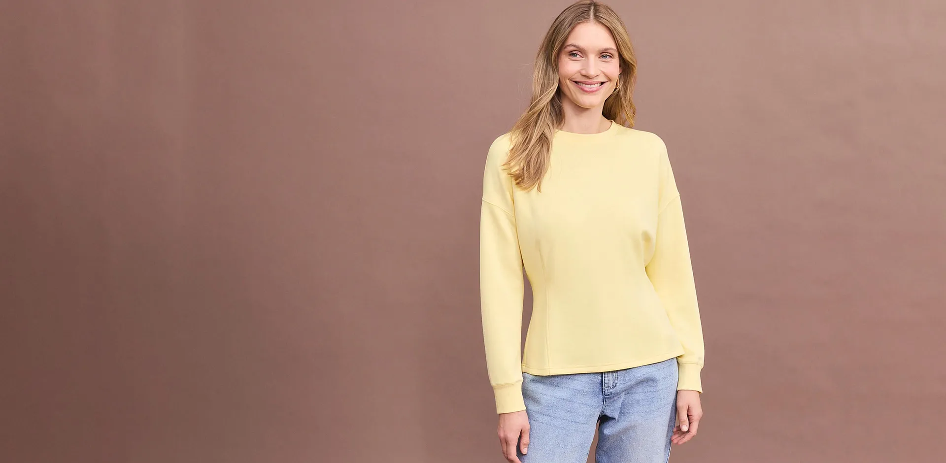 Maglia marrone a maniche lunghe con comodi jeans blu.