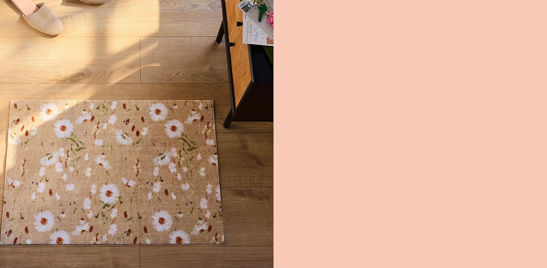 Comode pantofole su pavimento in legno accanto a uno zerbino floreale.