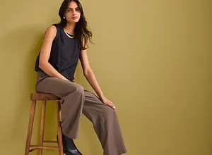 Top senza maniche blu scuro, pantaloni larghi marroni e stivaletti neri. Look elegante e casual.