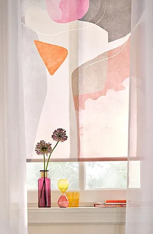 Tende chiare con forme astratte  incorniciano una finestra, assieme a fiori in vasi colorati. 