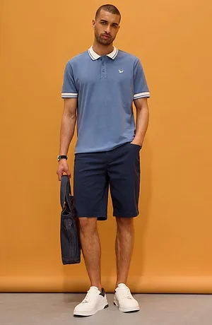 Polo azzurra con colletto bianco e pantaloni corti scuri. Look sportivo ed elegante per tutti i giorni.