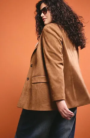 Blazer elegante color cammello con grandi bottoni, abbinato a gonna scura e occhiali da sole alla moda.