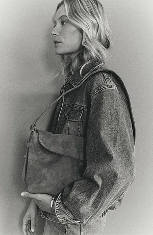 Una classica giacca di jeans con borchie, abbinata a una semplice borsa in similpelle per un look casual.