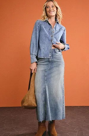 Look denim dalla testa ai piedi: giacca di jeans e gonna lunga di jeans abbinate a stivali marroni.