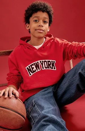 Felpa rossa con scritta New York e jeans blu.