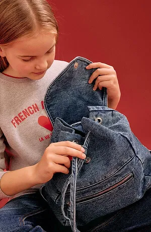 Felpa grigia con scritta rossa e zaino in denim blu. Look da bambini casual per tutti i giorni.