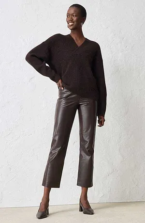 Maglione con scollo a V marrone scuro abbinato a pantaloni in similpelle e décolleté dello stesso colore.