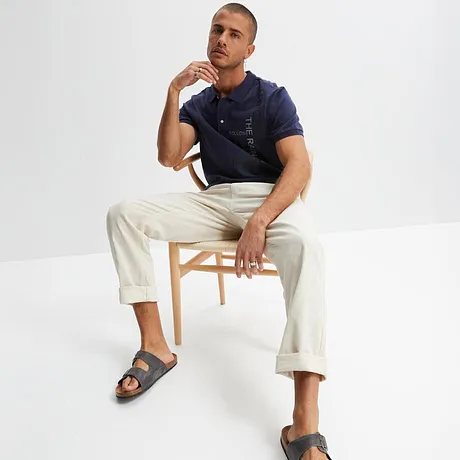  Polo blu scuro con pantaloni bianchi e sandali grigi. Look estivo casual per tutti i giorni. 