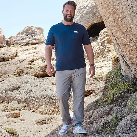 T-shirt blu con logo, pantaloni grigi e sneakers bianche. 