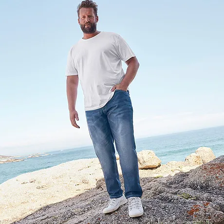 Look da spiaggia casual: t-shirt bianca e jeans rilassati, completati da comode sneakers bianche.