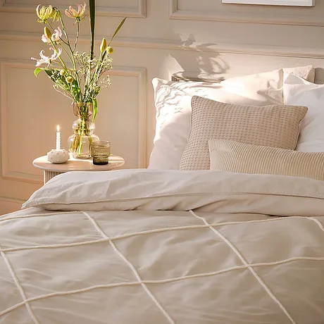 Biancheria da letto chiara con motivi a quadri decora la camera da letto luminosa, con cuscini e coperta che si armonizzano perfettamente. 