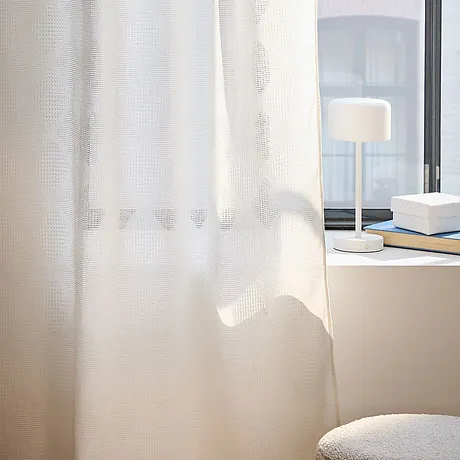 Tende bianche ariose adornano la finestra e filtrano dolcemente la luce del giorno.