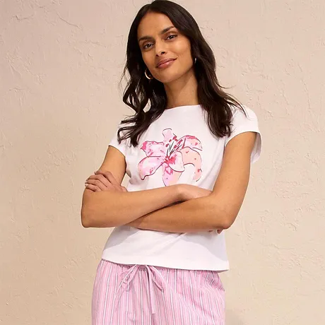 T-shirt bianca con stampa rosa, abbinata a pantaloni pigiama a righe, per un look casual e comodo. 