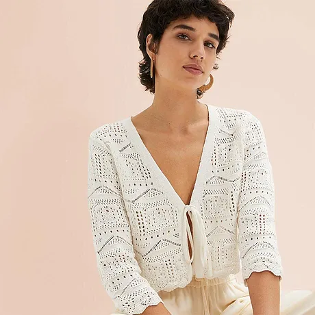 Cardigan bianco leggero con motivo traforato e laccetto, perfetto per le serate estive.