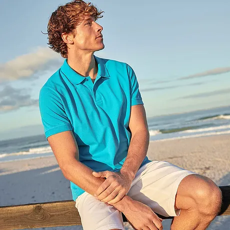 Look estivo da spiaggia: polo turchese e pantaloncini chiari per un'atmosfera vacanziera rilassata al mare.