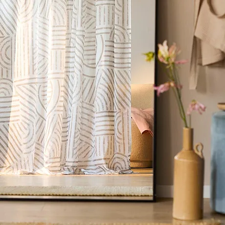 Tende leggere con motivi decorano la finestra e filtrano delicatamente la luce naturale. 