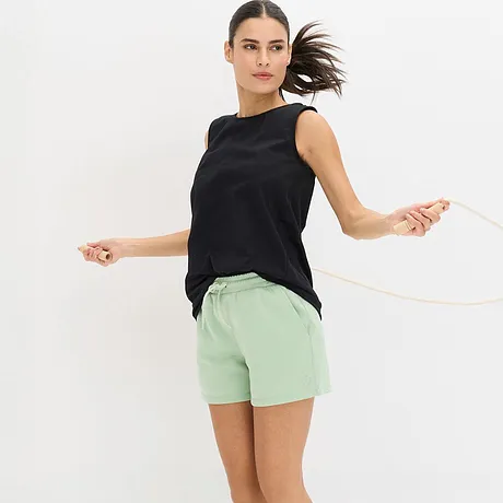 Top nero abbinato a shorts sportivi funzionali verde menta.