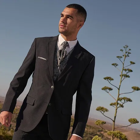 Elegante completo scuro con camicia bianca e cravatta a fantasia.