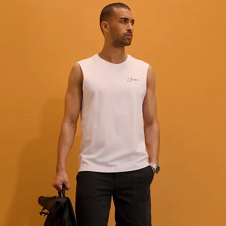 Canotta bianca, pantaloncini scuri, sneakers bianche e zaino nero.