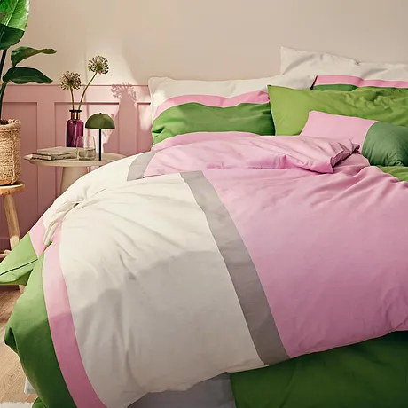 Biancheria da letto in rosa, bianco e verde adorna il letto accogliente nella camera da letto.