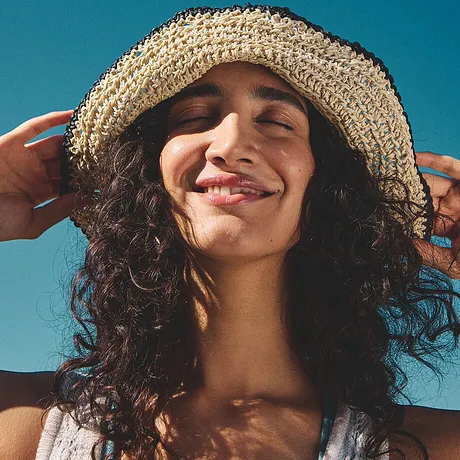 Cappello estivo in paglia intrecciata e top bianco fresco che trasmettono la leggerezza dell'estate e delle vacanze.