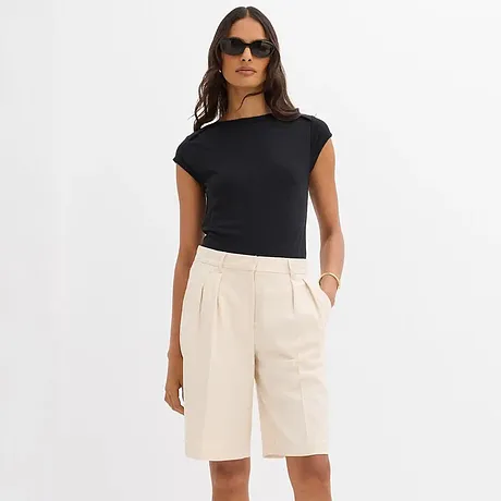 Combinazione elegante di t-shirt nera e bermuda color crema.