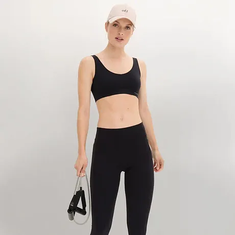 Top nero per sport, leggings per sport e cappello bianco.