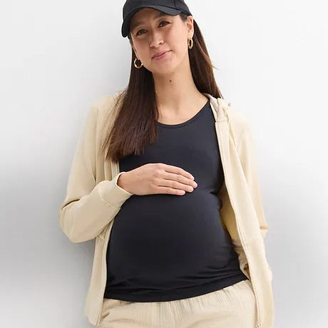 Moda prémaman comoda: cardigan color crema, top scuro e cappello sportivo.