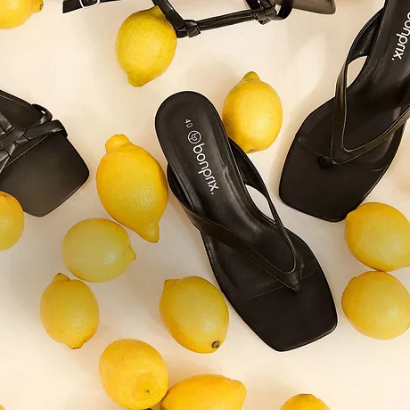 Sandali neri eleganti tra limoni gialli.