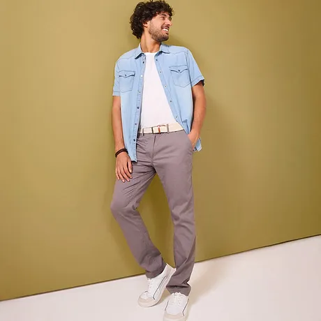 Pantaloni chino grigi abbinati a una camicia di jeans azzurra.