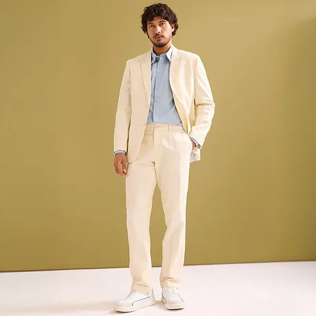 Completo elegante color crema con camicia azzurra e sneakers bianche.