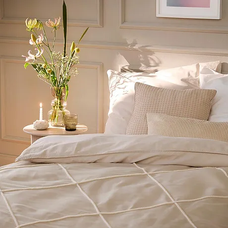 Biancheria da letto chiara con motivi geometrici adorna il letto. Cuscini e coperte bianche creano un'atmosfera invitante.