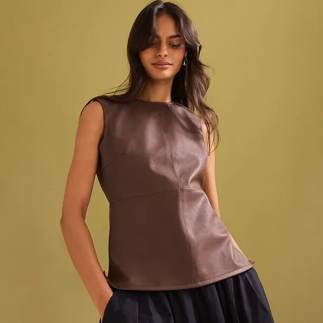  Elegante top in similpelle marrone senza maniche, abbinato a una gonna scura e orecchini discreti.