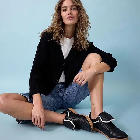  Giacca nera, maglietta bianca, shorts di jeans e sneakers nere alla moda.