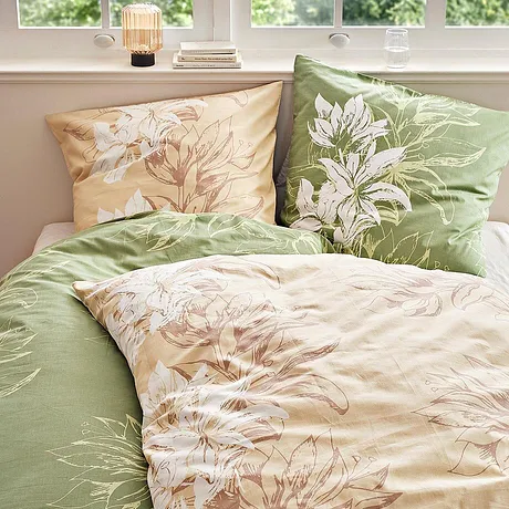 Biancheria da letto floreale in tonalità pastello: verde e beige con delicati motivi floreali decorano il letto.