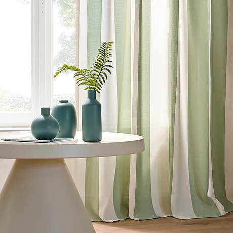 Una tenda chiara in verde pastello e bianco decora la finestra, conferendo eleganza alla stanza.