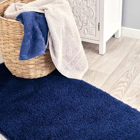 Morbidi asciugamani in blu e beige riposano nel cesto su un tappeto soffice.
