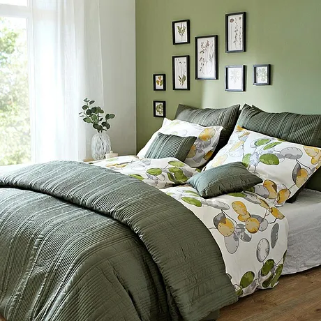 Camera da letto accogliente con lenzuola e cuscini verdi. I motivi floreali sulle lenzuola conferiscono freschezza.