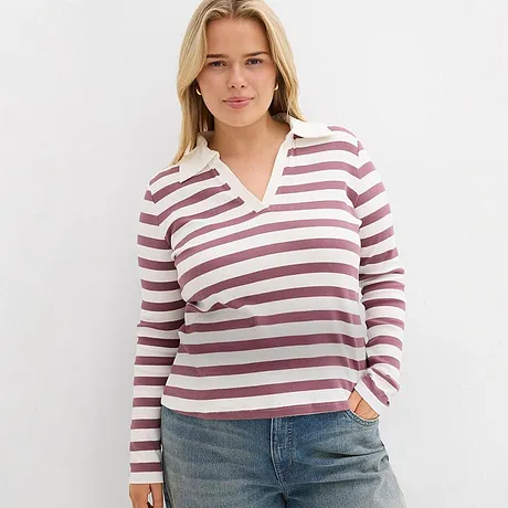 Maglia a maniche lunghe rosa e bianca, abbinata a jeans chiari.