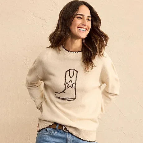 Maglione color crema con stivale, abbinato a jeans blu.