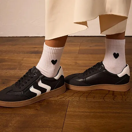 Calzini bianchi con cuoricini, sneaker nere con strisce bianche.